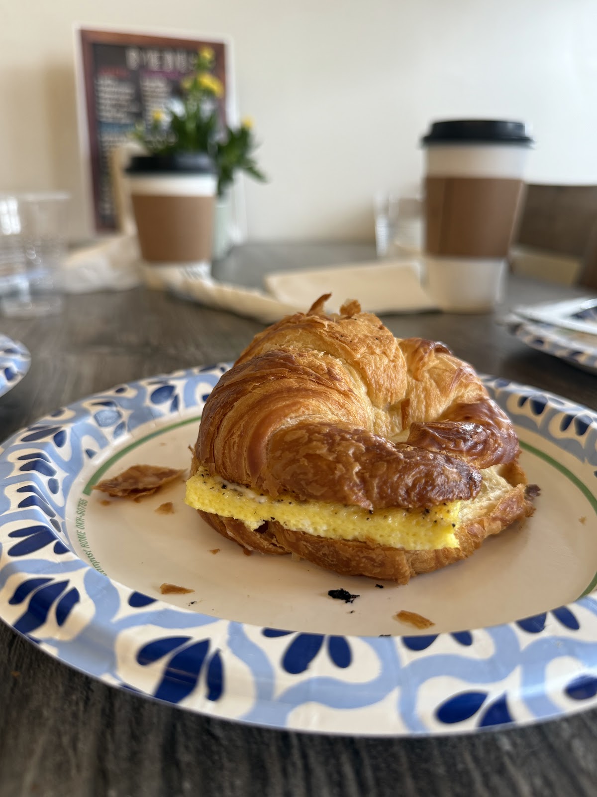 An egg and cheese croissant sandwich on a patterned plate